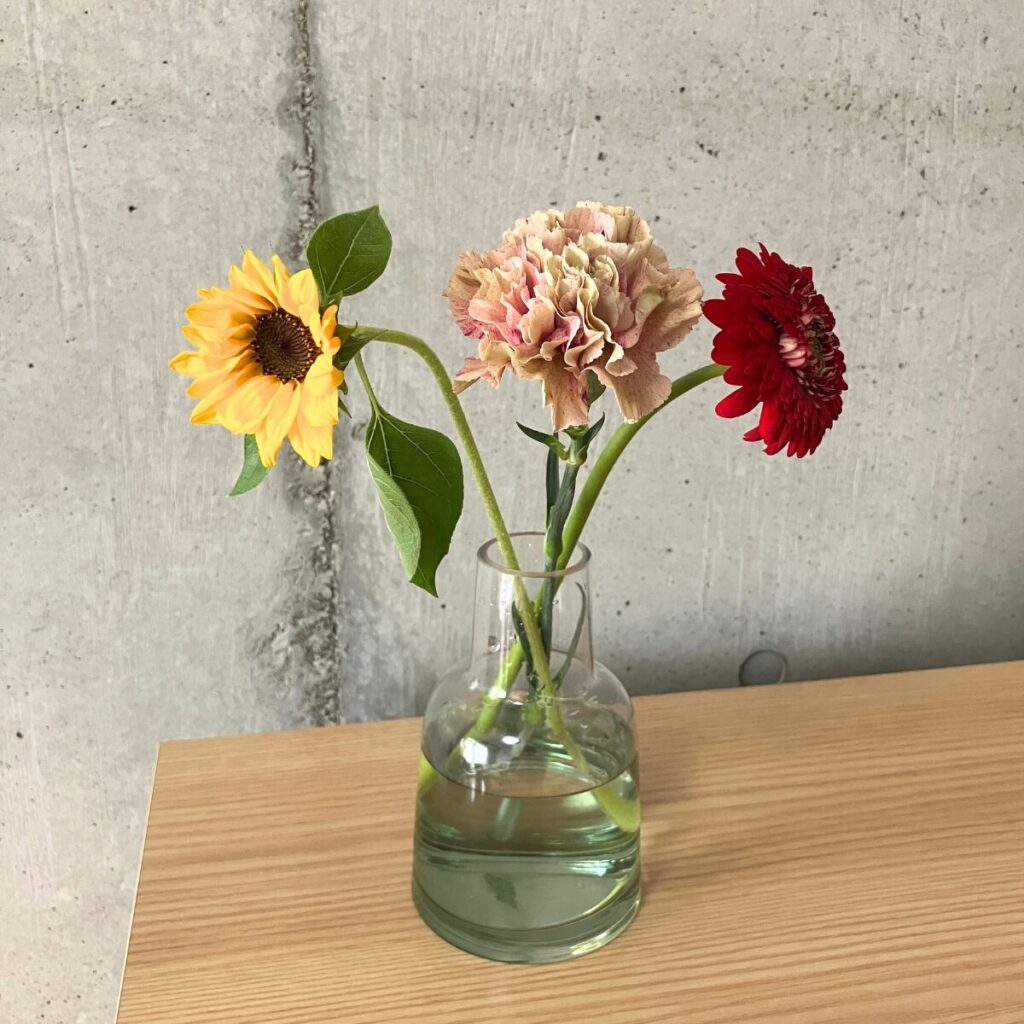 花の定期便＋hana（タスハナ）の+ act for flowersプランで届いたお花ガーベラ、ひまわり、カーネーションの計3本を花瓶に生けた様子