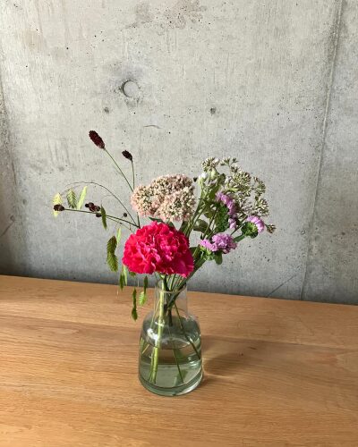 medeluのANYROOMコースのボリュームLite+のお花を緑の透明ガラス花瓶に生けている様子