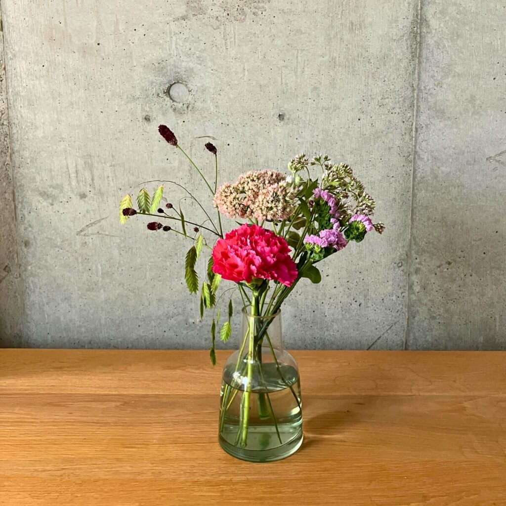 medeluのANYROOMコースのボリュームLite+のお花をグリーンの透明ガラス花瓶に生けた様子