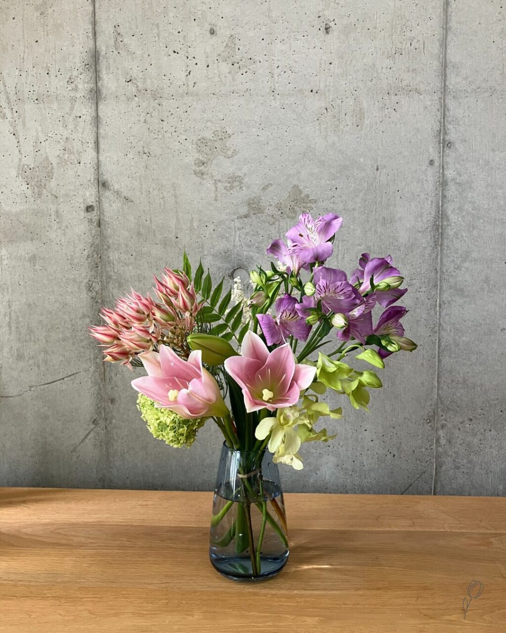 medeluのANYROOMコースのボリュームBasicのお花を青の透明ガラス花瓶に生けた様子