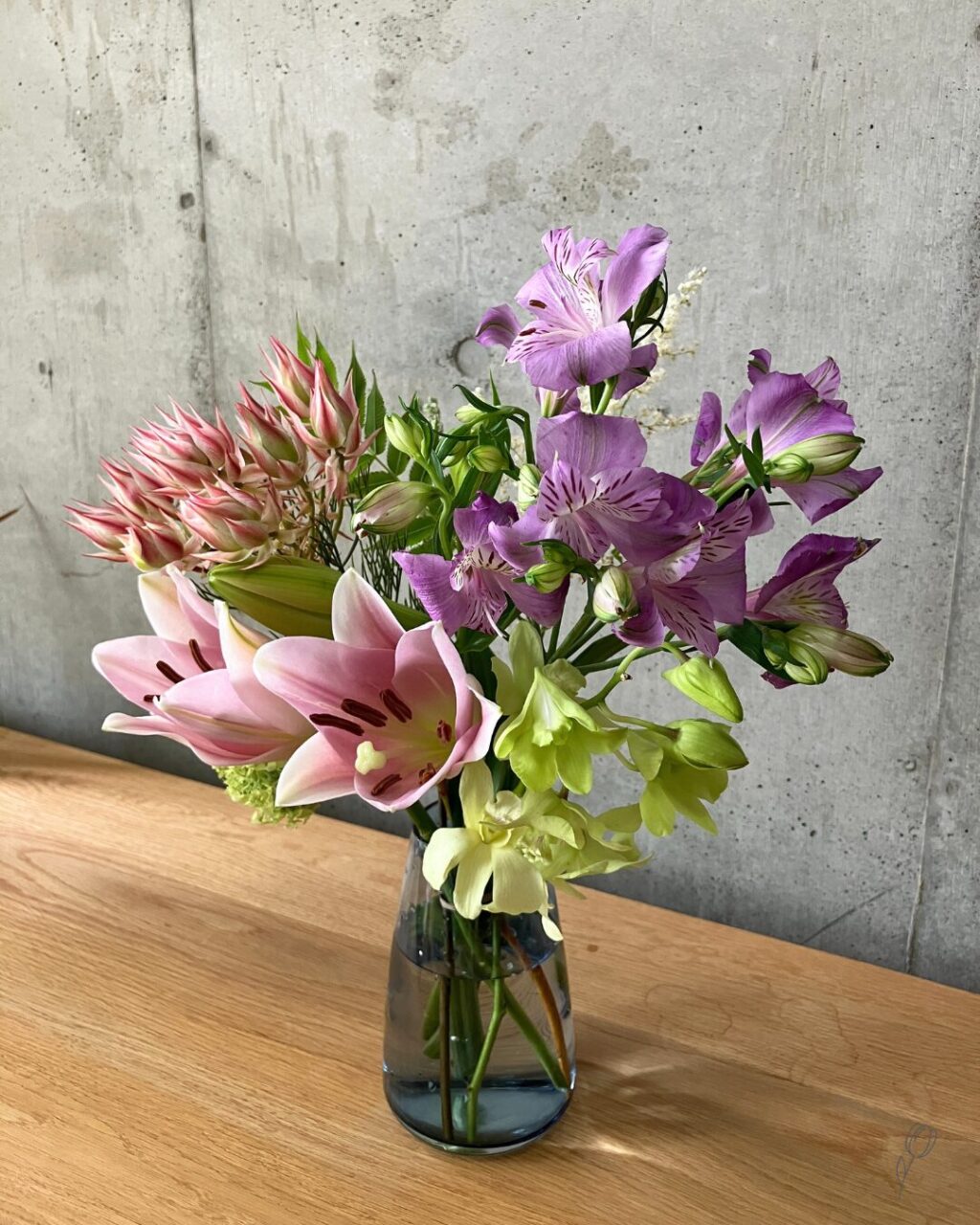 medeluのANYROOMコースのボリュームBasicのお花を青の透明ガラス花瓶に生けて斜め上から撮影した様子