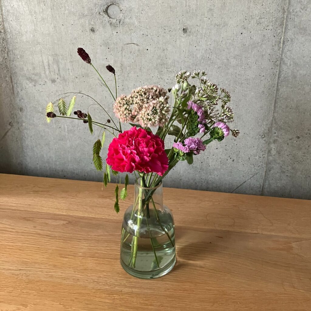 medeluのANYROOMコースのボリュームLite+のお花を緑の透明ガラス花瓶に生けている様子