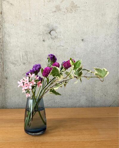 千日紅、スターチスなどのピンク＆パープル系のお花をブルーの色付きの花瓶に生けた様子