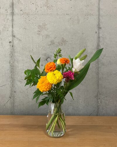 マリーゴールドなどのイエロー＆オレンジ系のお花をクリア（透明）の花瓶に生けた様子