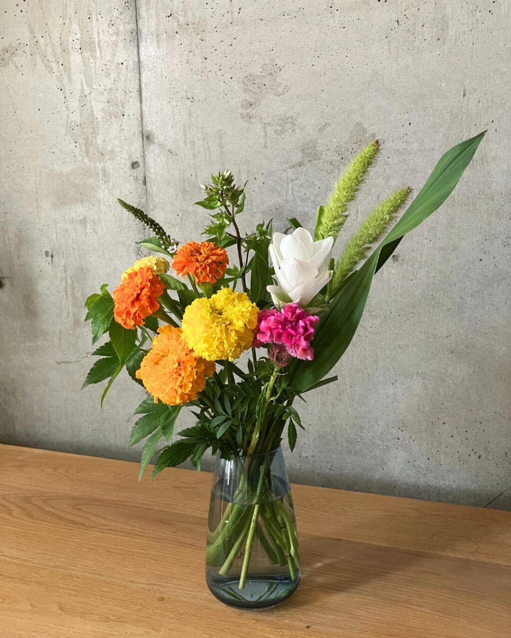 AQUA CULTURE VASEのサイズLのブルーに花の定期便LIFFTのお花（マリーゴールドなど）を生けた様子
