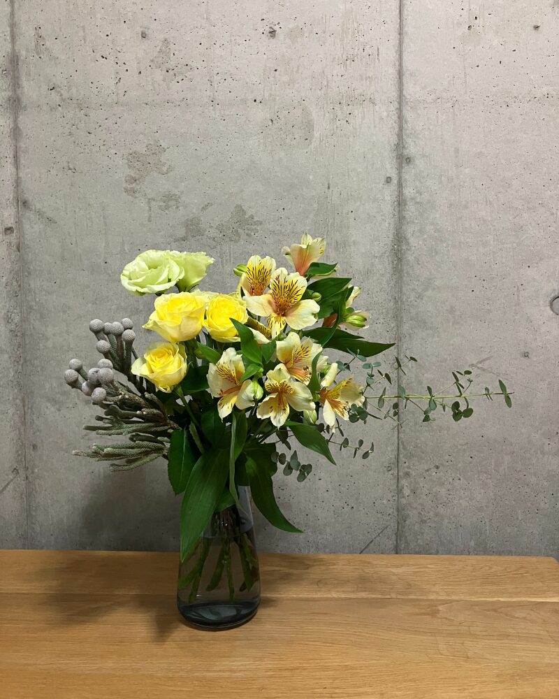 青山フラワーマーケット旬の花定期便Mを青の透明ガラス花瓶に生けた様子