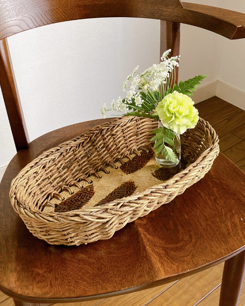 カーネーションとレースフラワーを小さな花瓶に生けて底がタイルになっているカゴに飾った様子