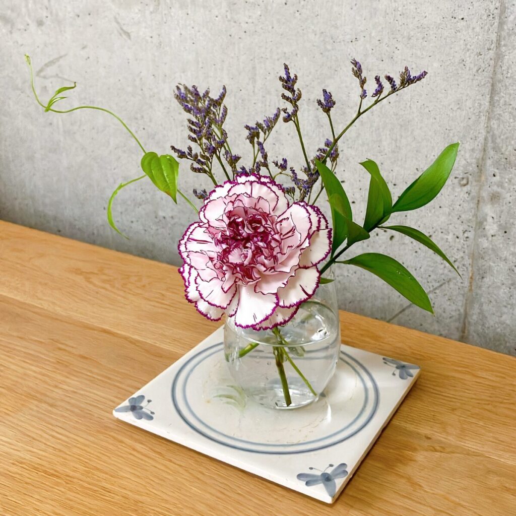 ブルーミーから届いたお花を置きカゴに飾っている様を花瓶に生けて、タイルの上に飾っている様子