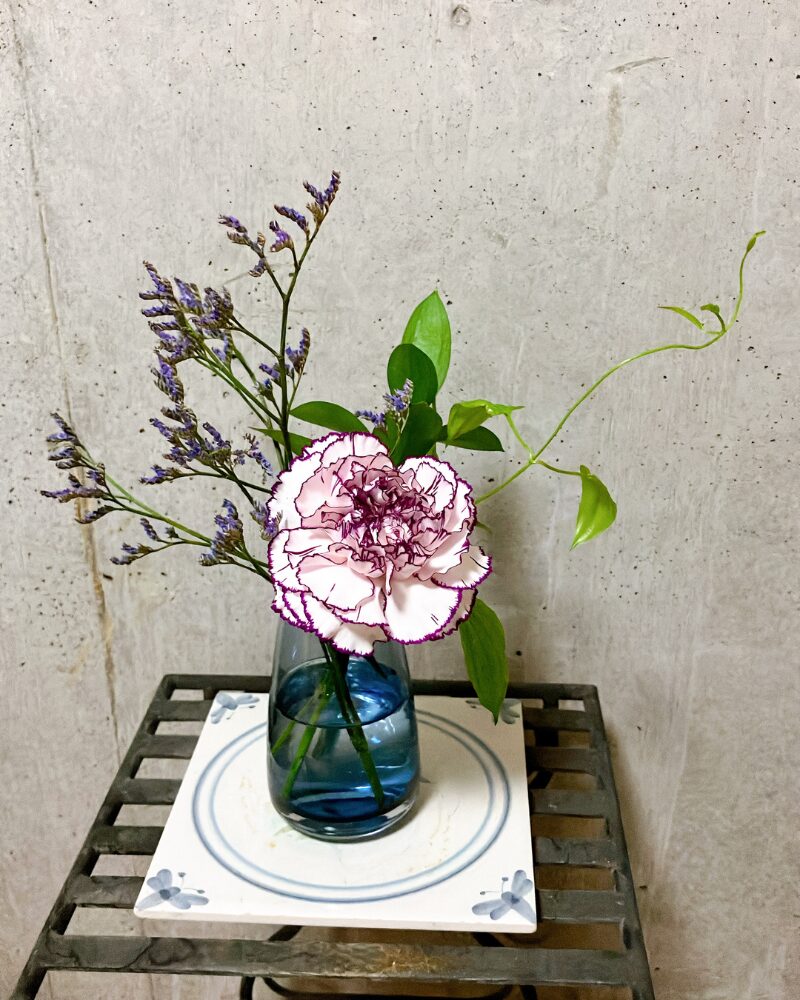 ブルーミーから届いたお花を置きカゴに飾っている様を花瓶に生けて、タイルの上に飾っている様子