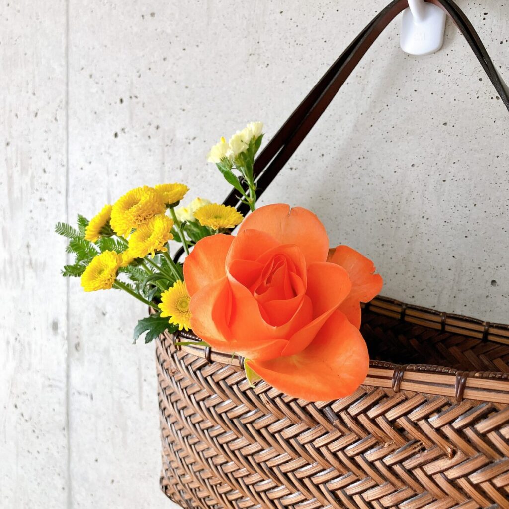 ブルーミーから届いたお花を壁掛けのかごバッグに飾っている様子をアップにした写真