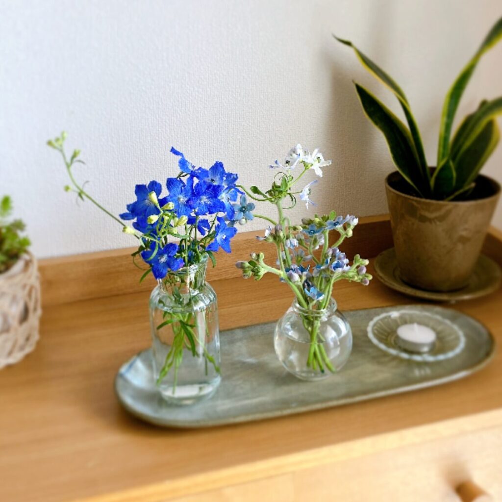 Blue Star and Delphinium styled on a long ceramic plate with a low white candle