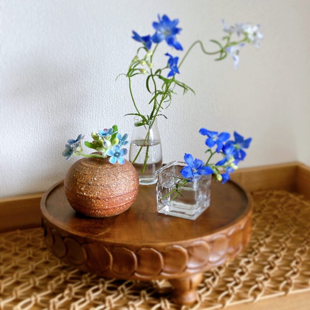 A stylish arrangement of Blue Star and Delphinium in mixed glass and Japanese ceramic vases on a pedestal compote