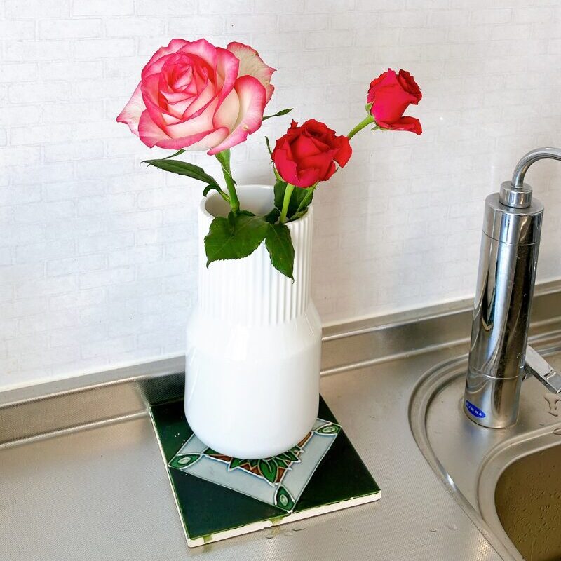 3本のバラを生けた花瓶の下にタイルを敷いている様子