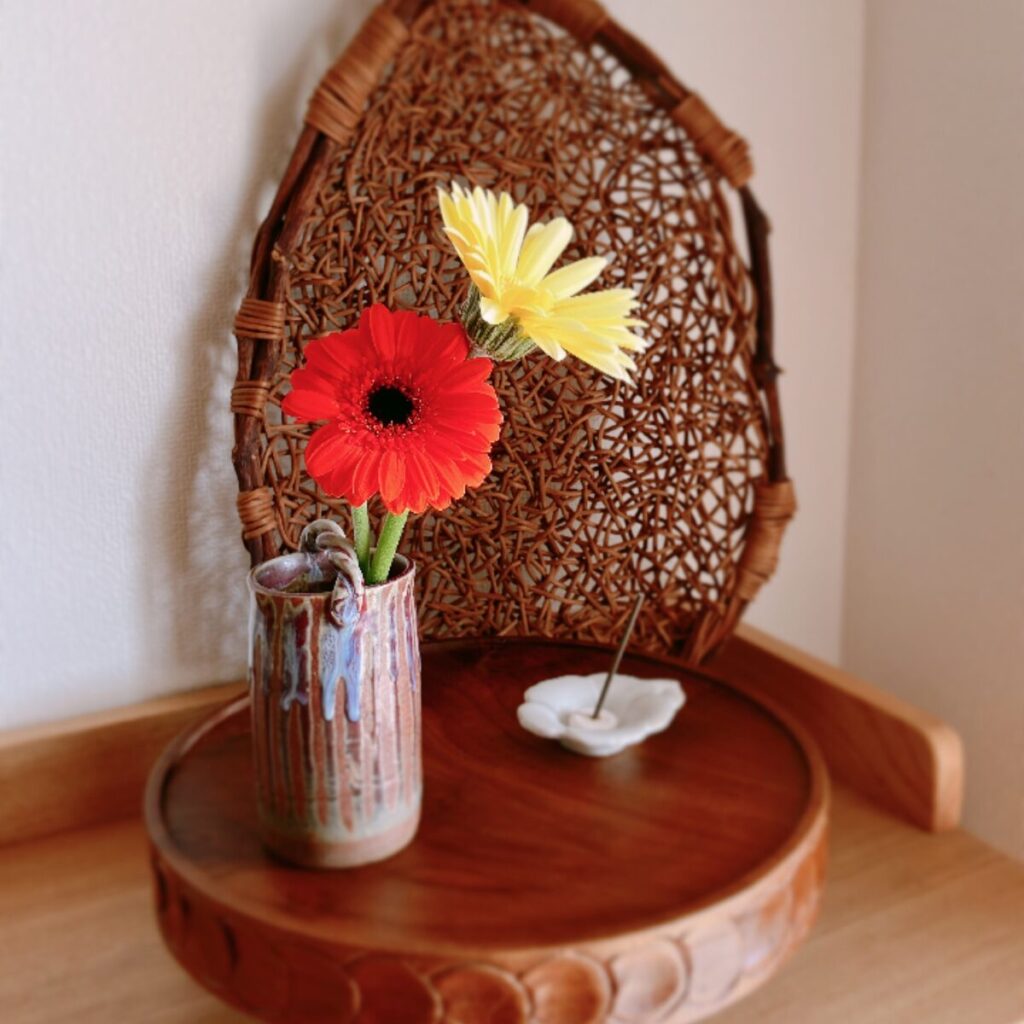 Yellow and orange gerberas in a Japanese ceramic vase on a compote with incense