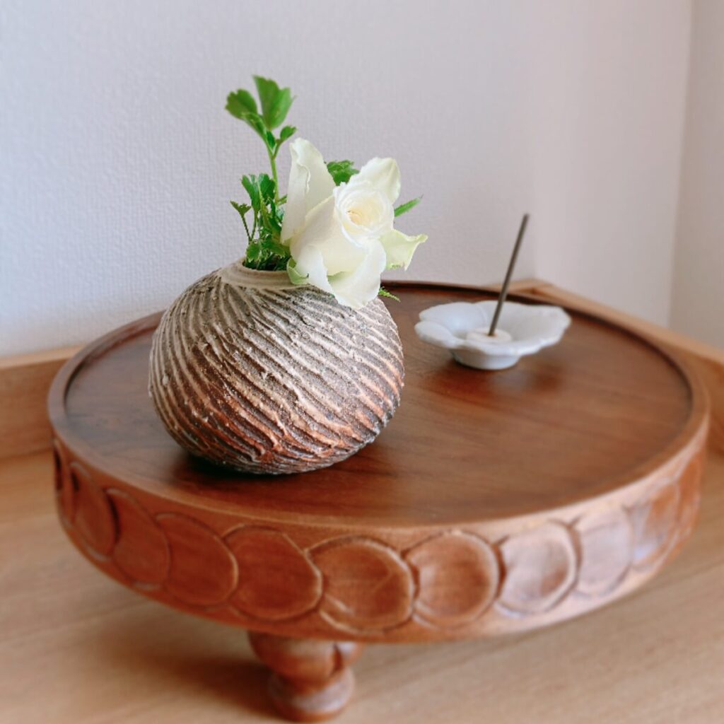 Greenery and rose in a round vase with a white flower bean plate