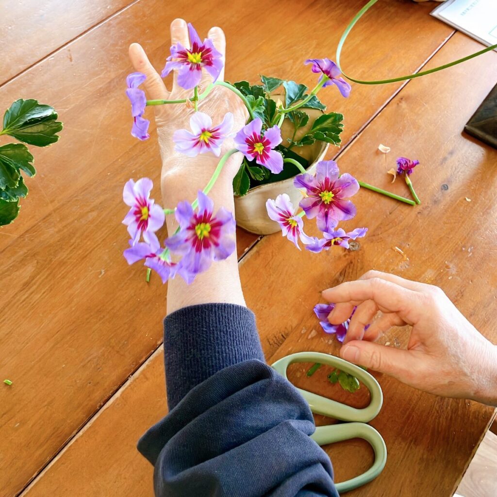 Adding green foliage to the base of the Leucocoryne arrangement to create a grounded look