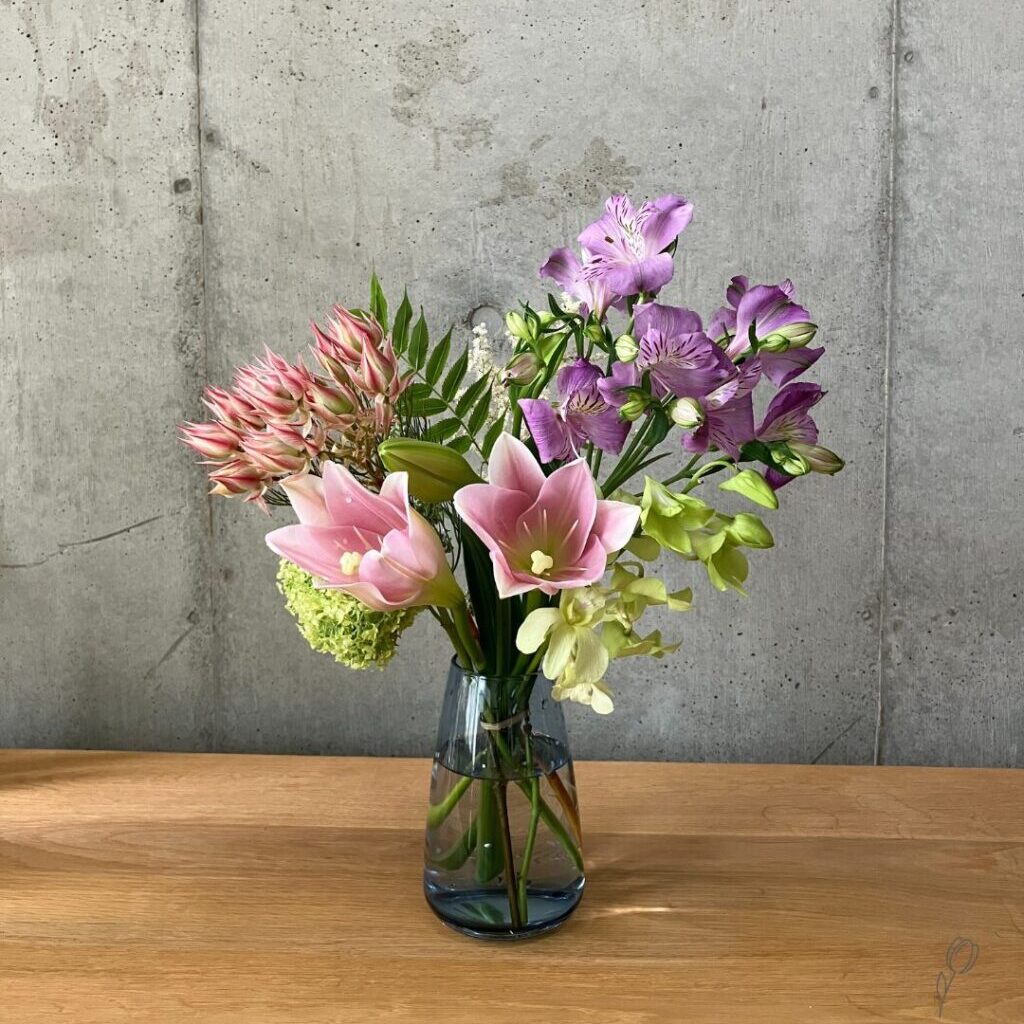 medeluのANYROOMコースのボリュームBasicのお花を青の透明ガラス花瓶に生けた様子