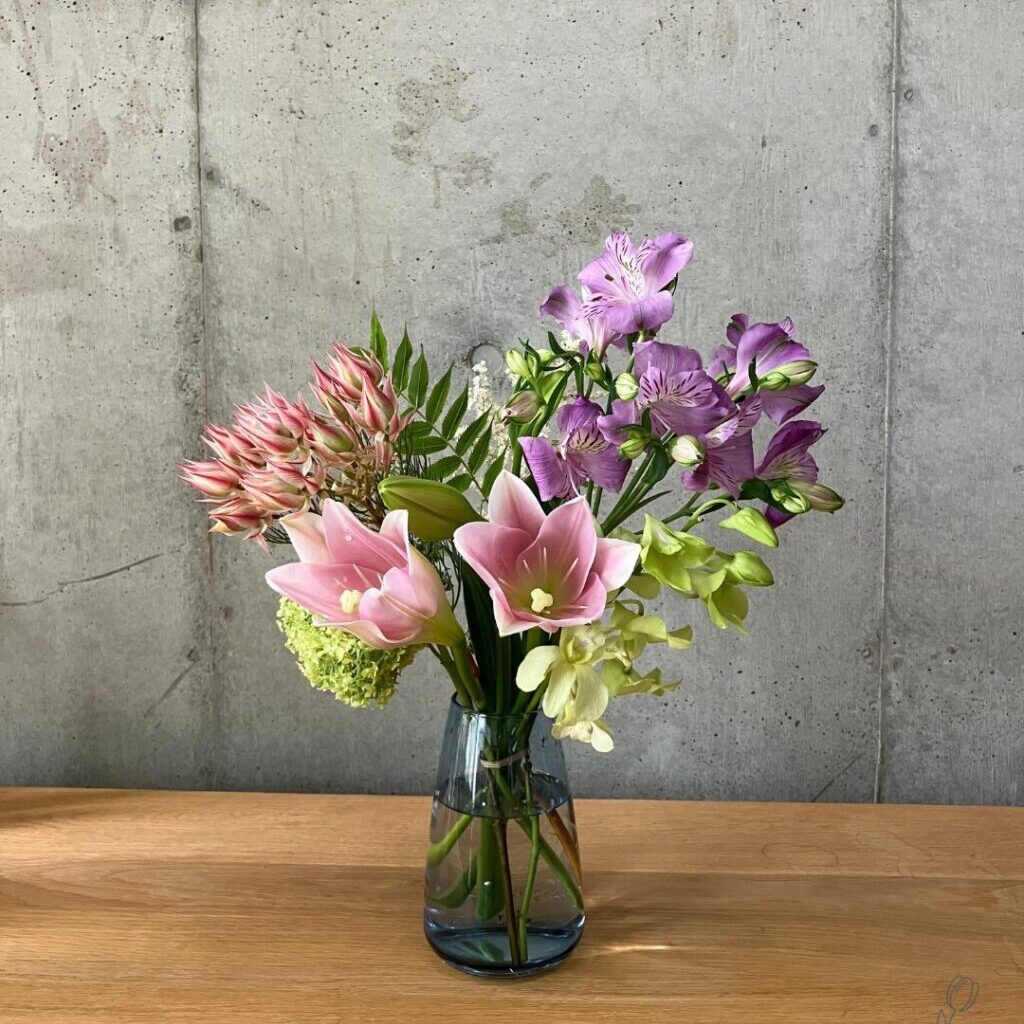 AQUA CULTURE VASEのサイズLのブルーに花の定期便medeluのお花（テッポウユリなど）を生けた様子