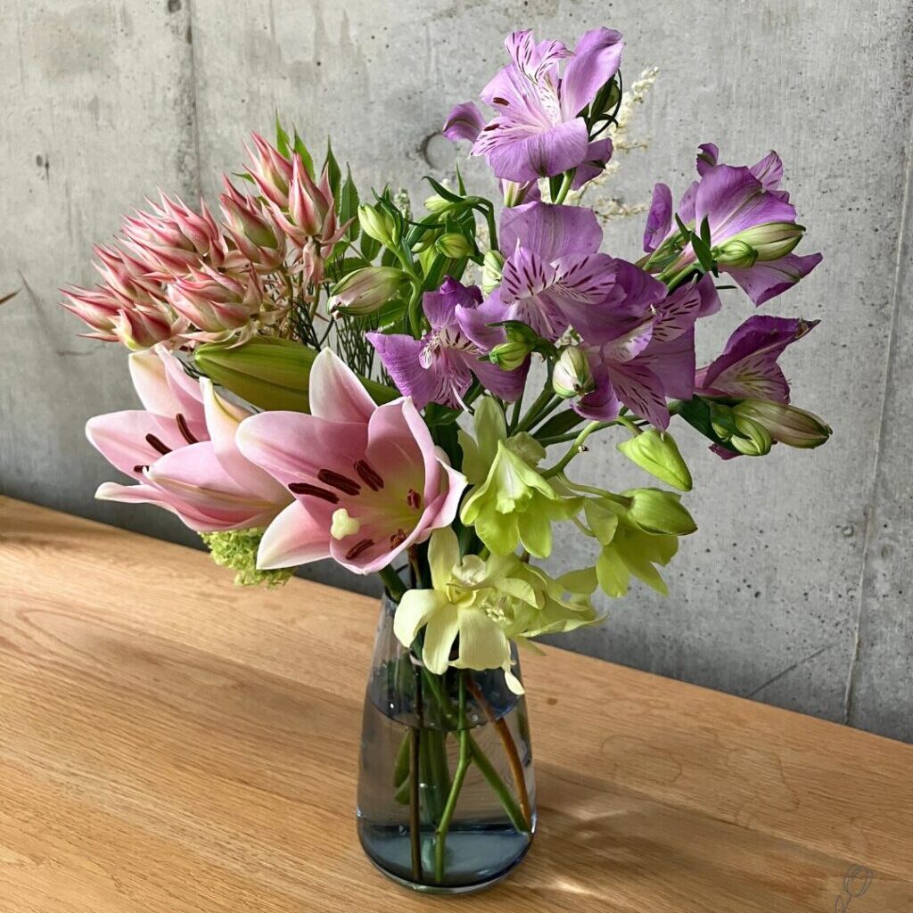 medeluのANYROOMコースのボリュームBasicのお花を青の透明ガラス花瓶に生けて斜め上から撮影した様子