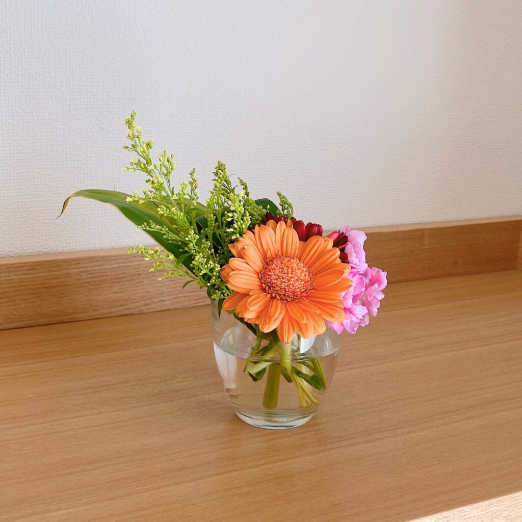 Gerbera and greens in a clear drinking glass