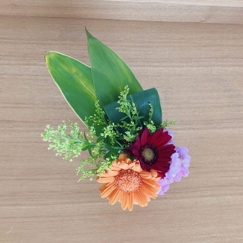 Gerbera and greens in a clear drinking glass top view