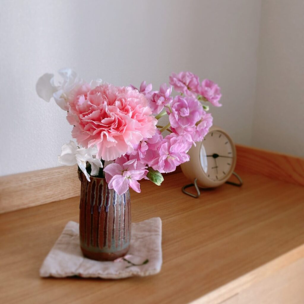 ピンクのカーネーションとストックを和の花瓶に入れた様子
