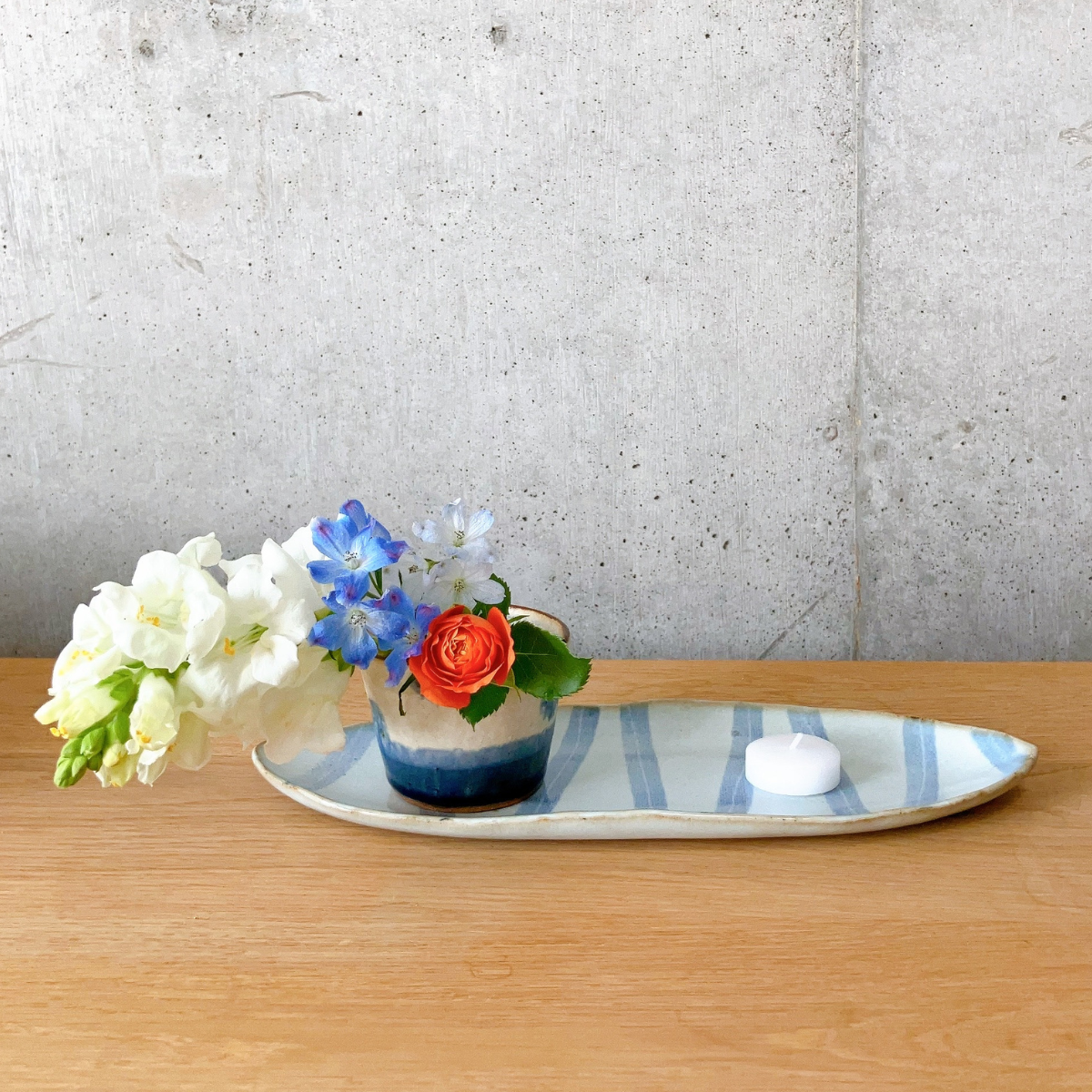 蕎麦猪口にお花を生け、ろうそくと一緒にお皿に乗せた様子