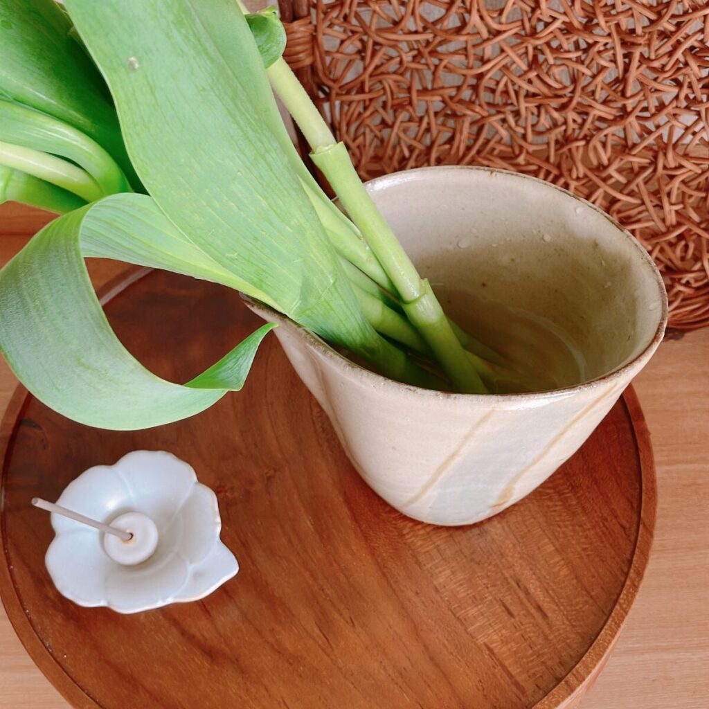 Close-up of tulip stems standing naturally in water inside a ceramic cup without floral foam