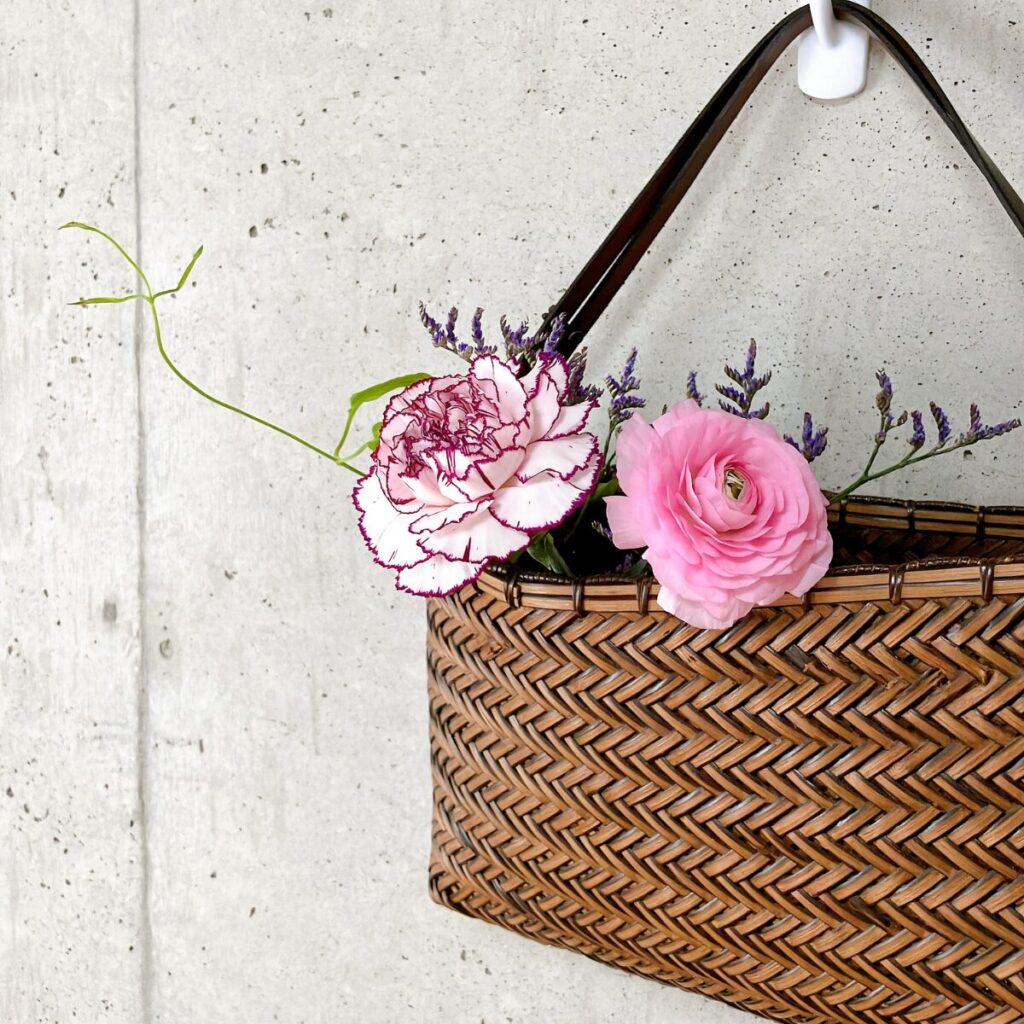 カーネーションとラナンキュラスを壁掛けかごに飾っている様子