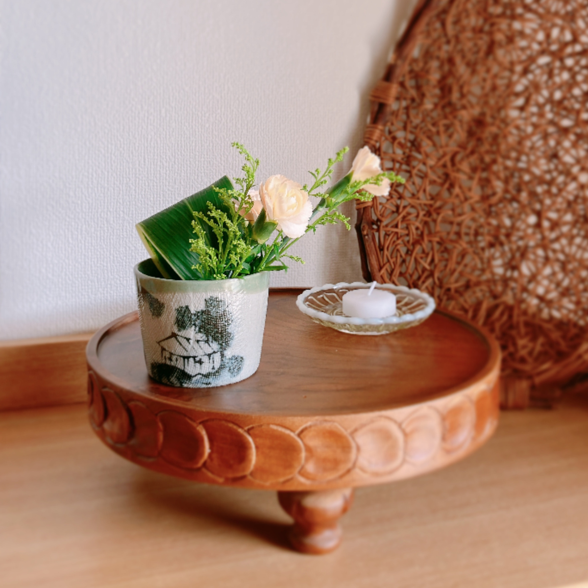 木のコンポートに蕎麦猪口に生けた花とろうそくを置いた様子