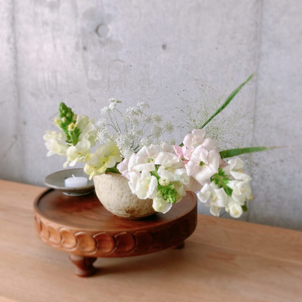 White snapdragons and laceflowers in an ivory Japanese noodle bowl on a wooden compote