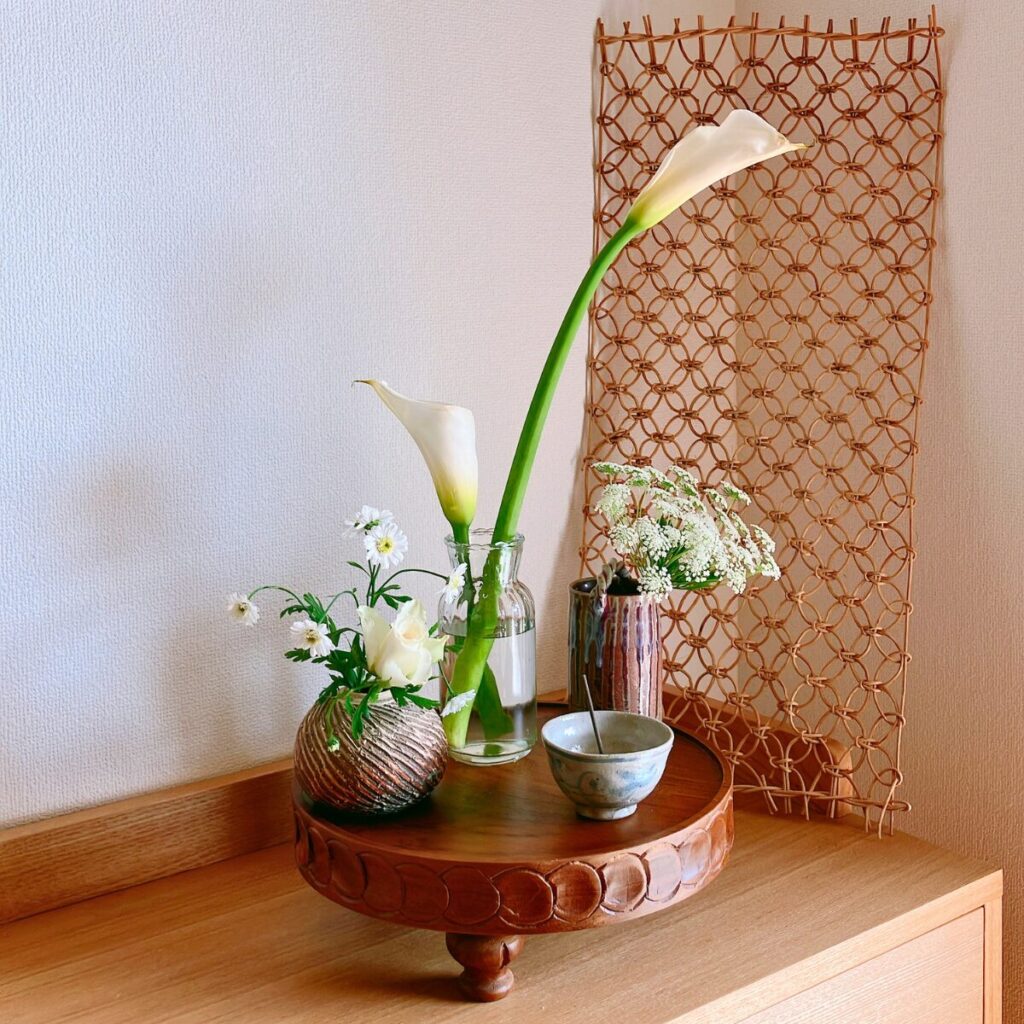 Monochromatic white calla lilies and roses in mixed ceramic and glass vases on a wooden compote