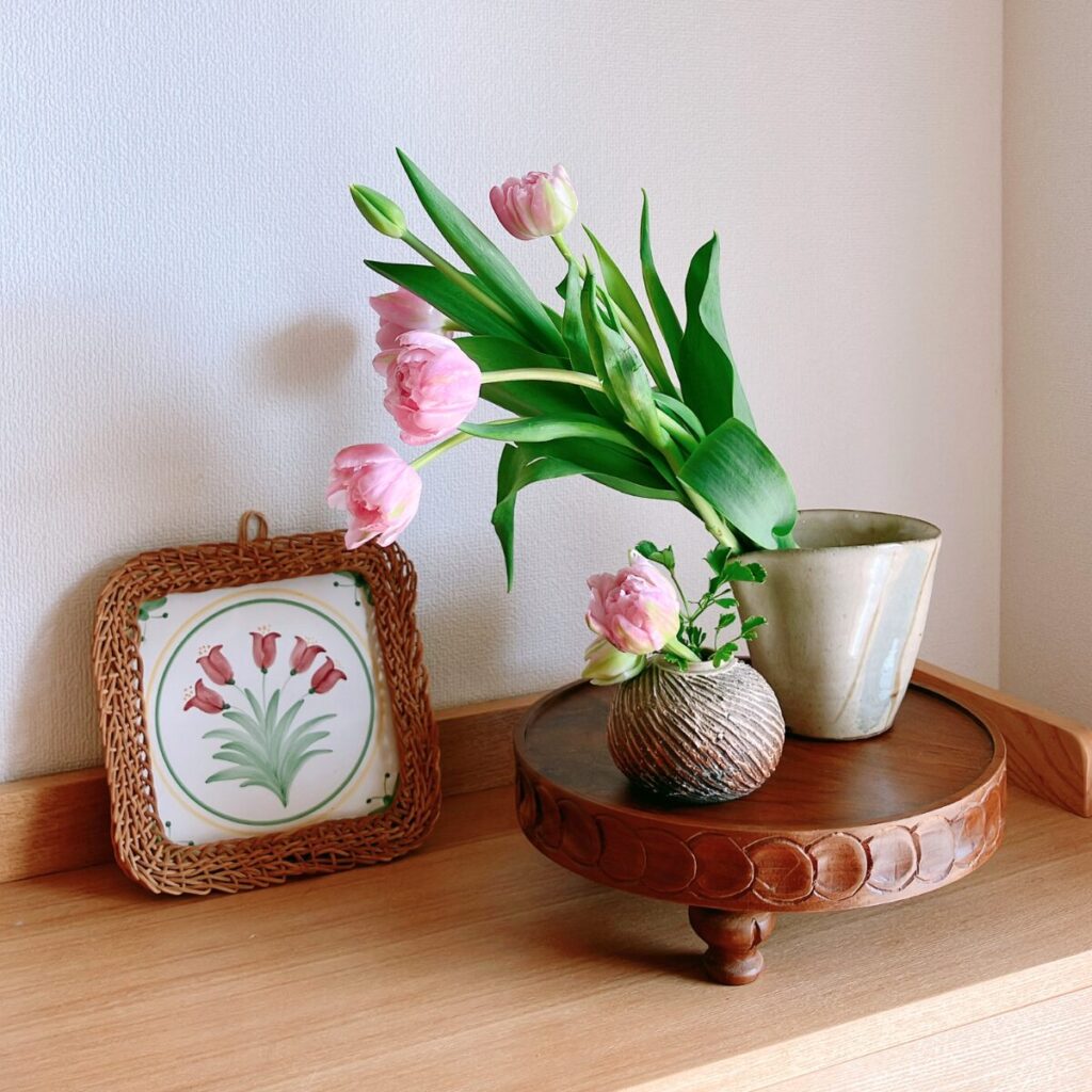 Pink tulips in a Japanese soba-tsuyu cup on a wooden stand with a tulip art tile