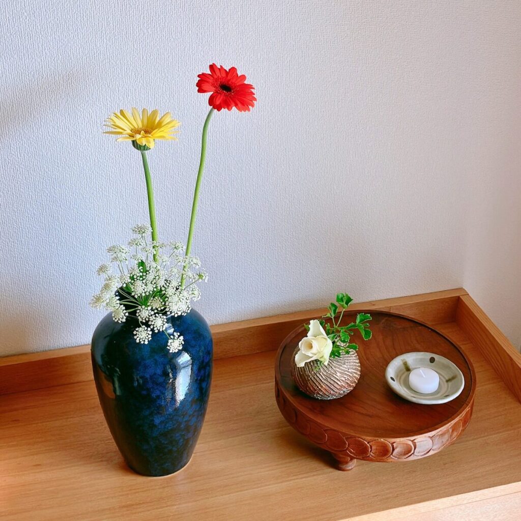 Dynamic spring table styling with a large vase of gerberas and a wooden compote with roses