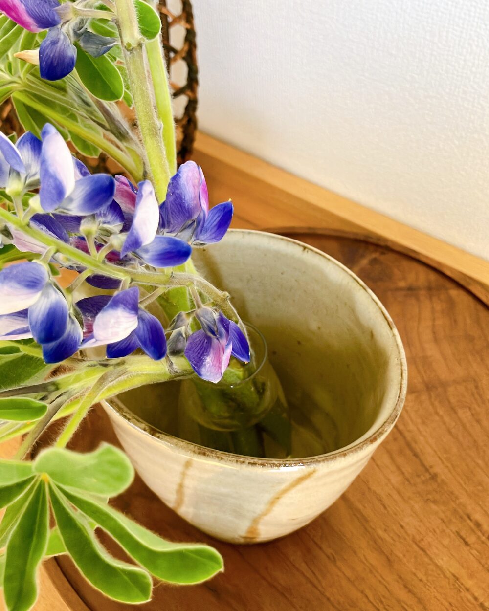 Close-up of a small glass vase hidden inside a ceramic pitcher to support flower stems