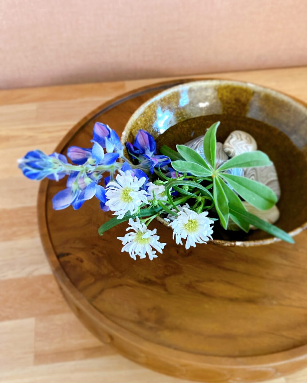 Top view of an Ikebana-style arrangement using ceramic stones as decorative weights in a shallow bowl