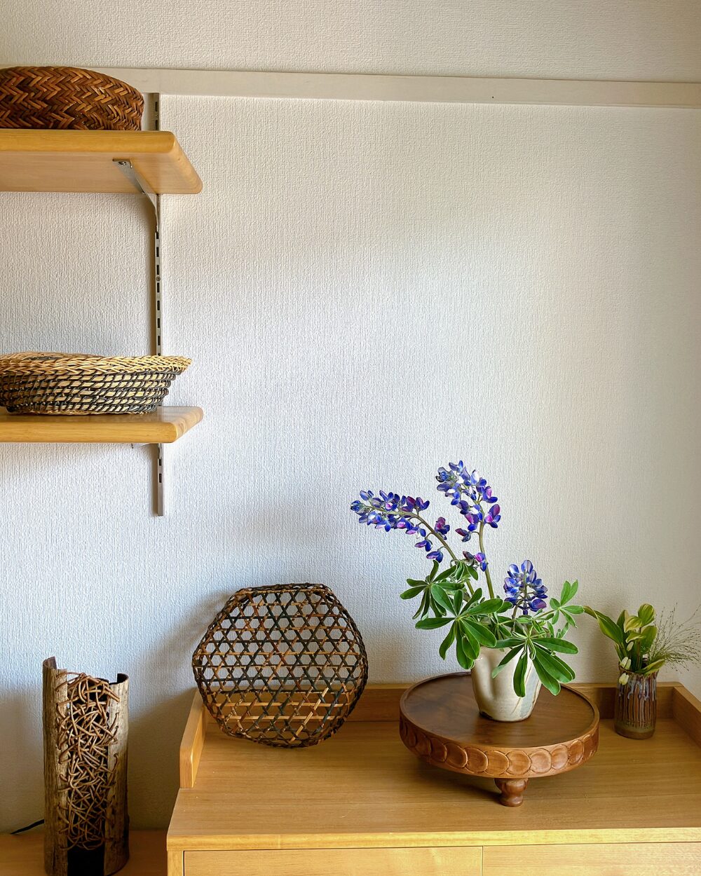 Japandi-style interior decor featuring blue lupinus flowers, woven baskets, and Japanese pottery