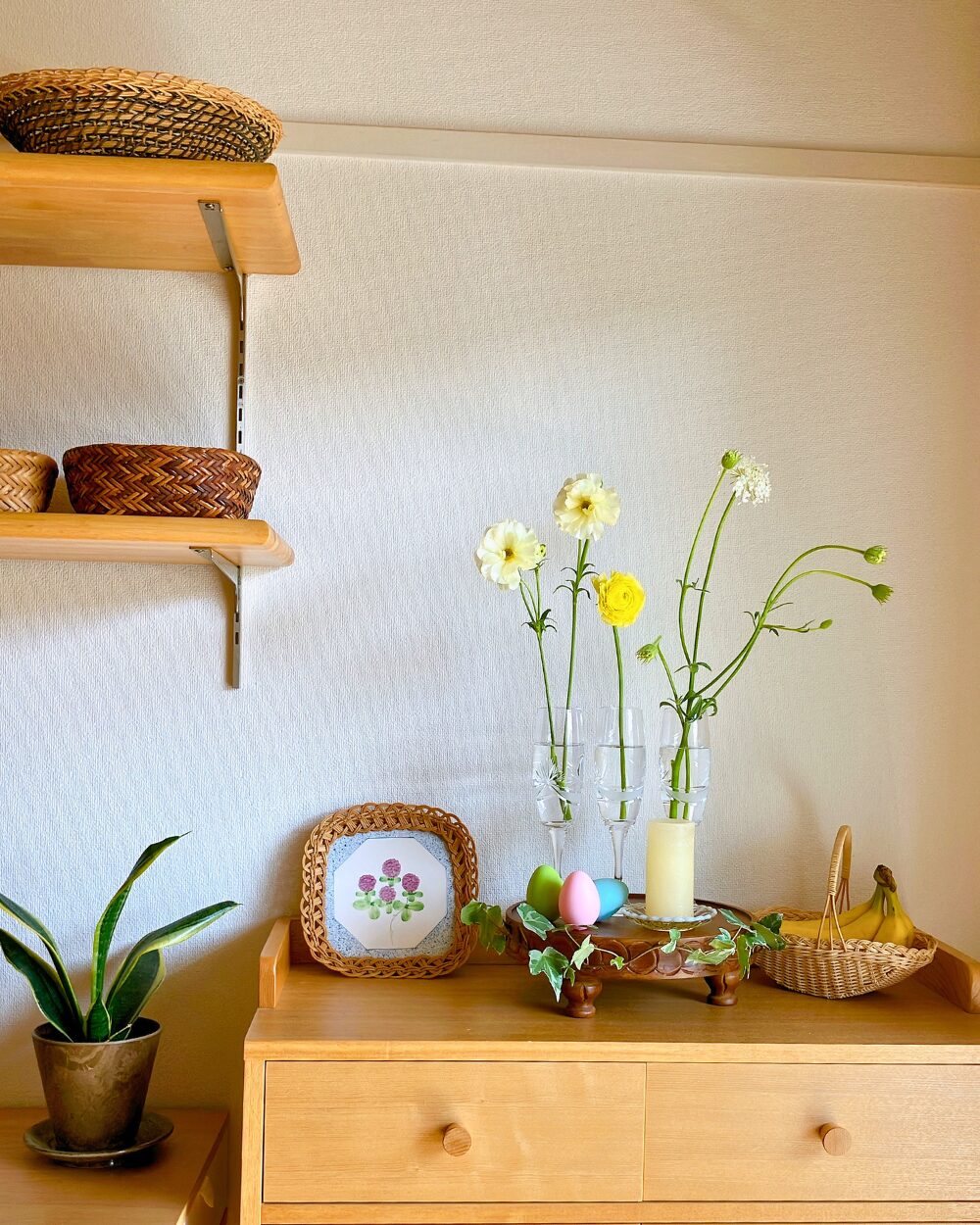 Minimalist Easter styling with flowers in three champagne glasses on a wooden compote
