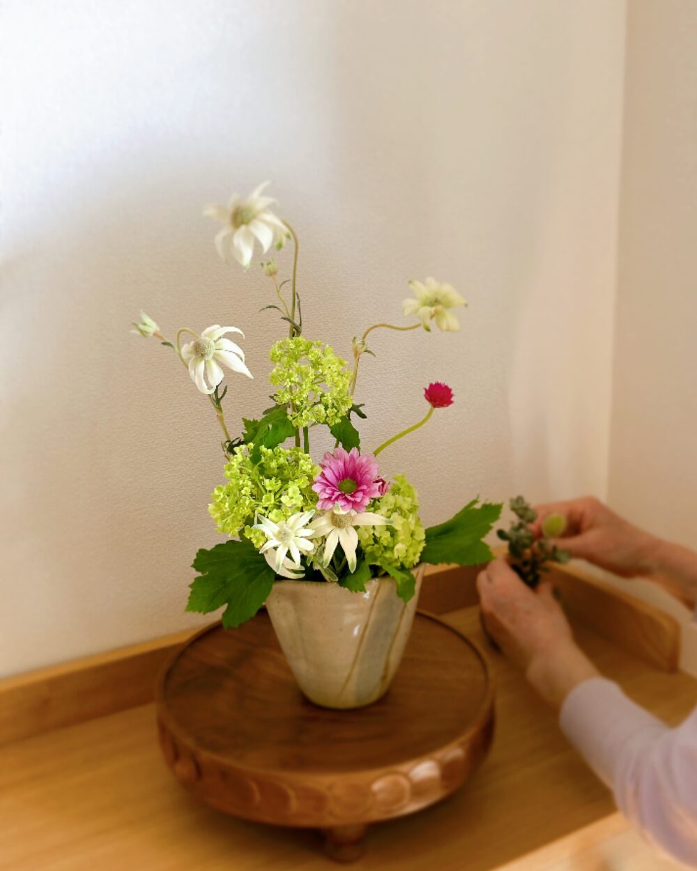 A Modern Wabi-Sabi arrangement of three Viburnum Snowballs and Flannel Flowers in a ceramic Soba-tsuyu pitcher