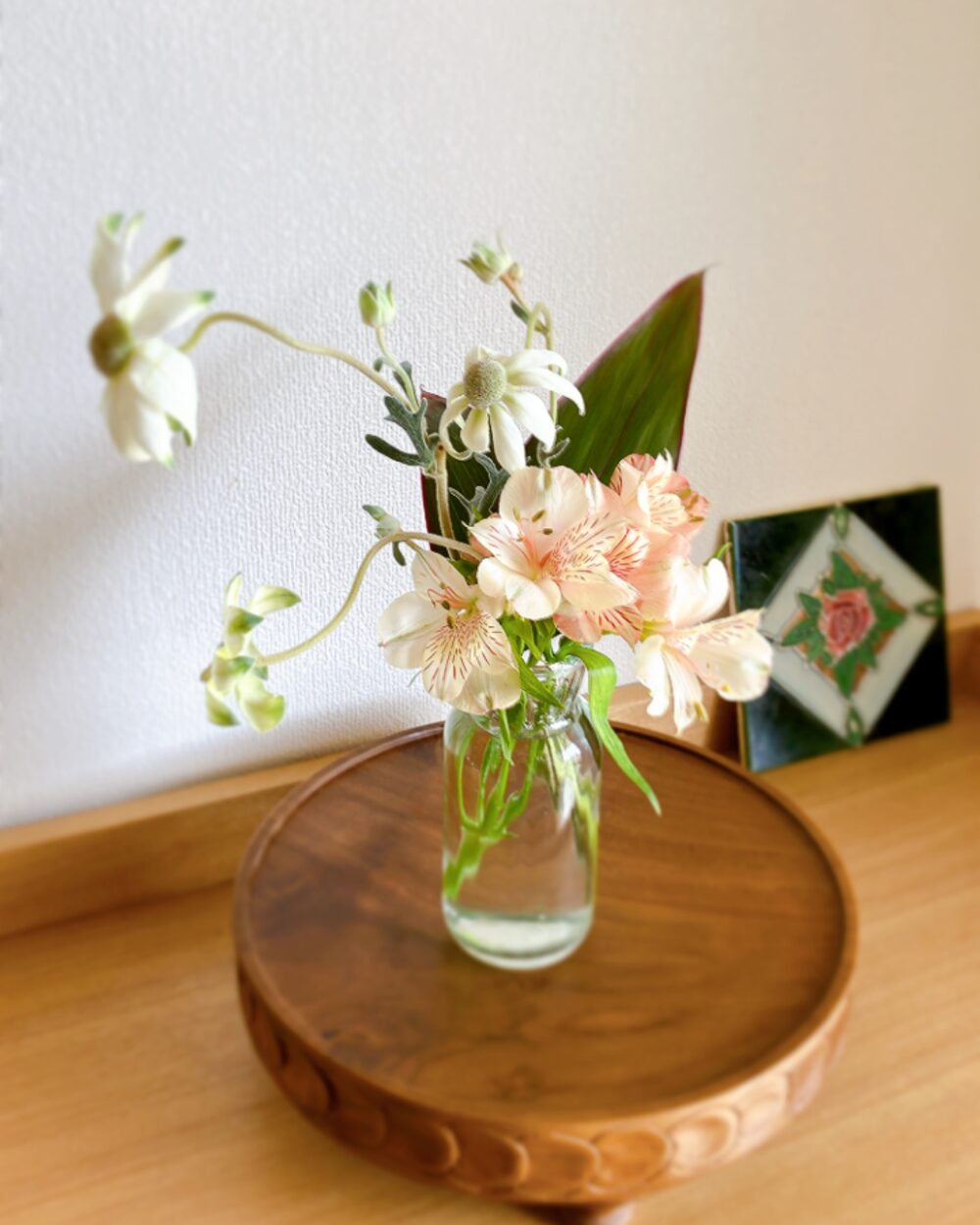 A simple arrangement of alstroemeria, flannel flowers, and dracaena leaves in a minimal vase
