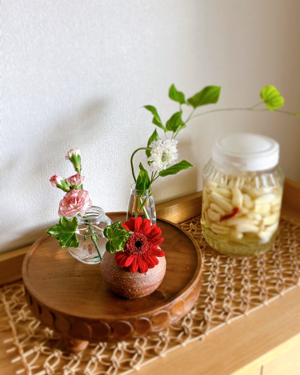 A close-up of red and white flowers in different glass and ceramic vessels, highlighting the fresh textures.