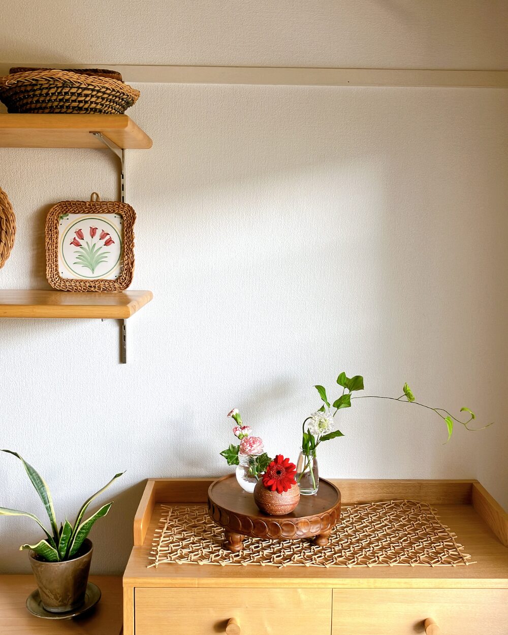 A wide shot of the entire shelf display featuring the multiple small vases filled with red and white flowers.