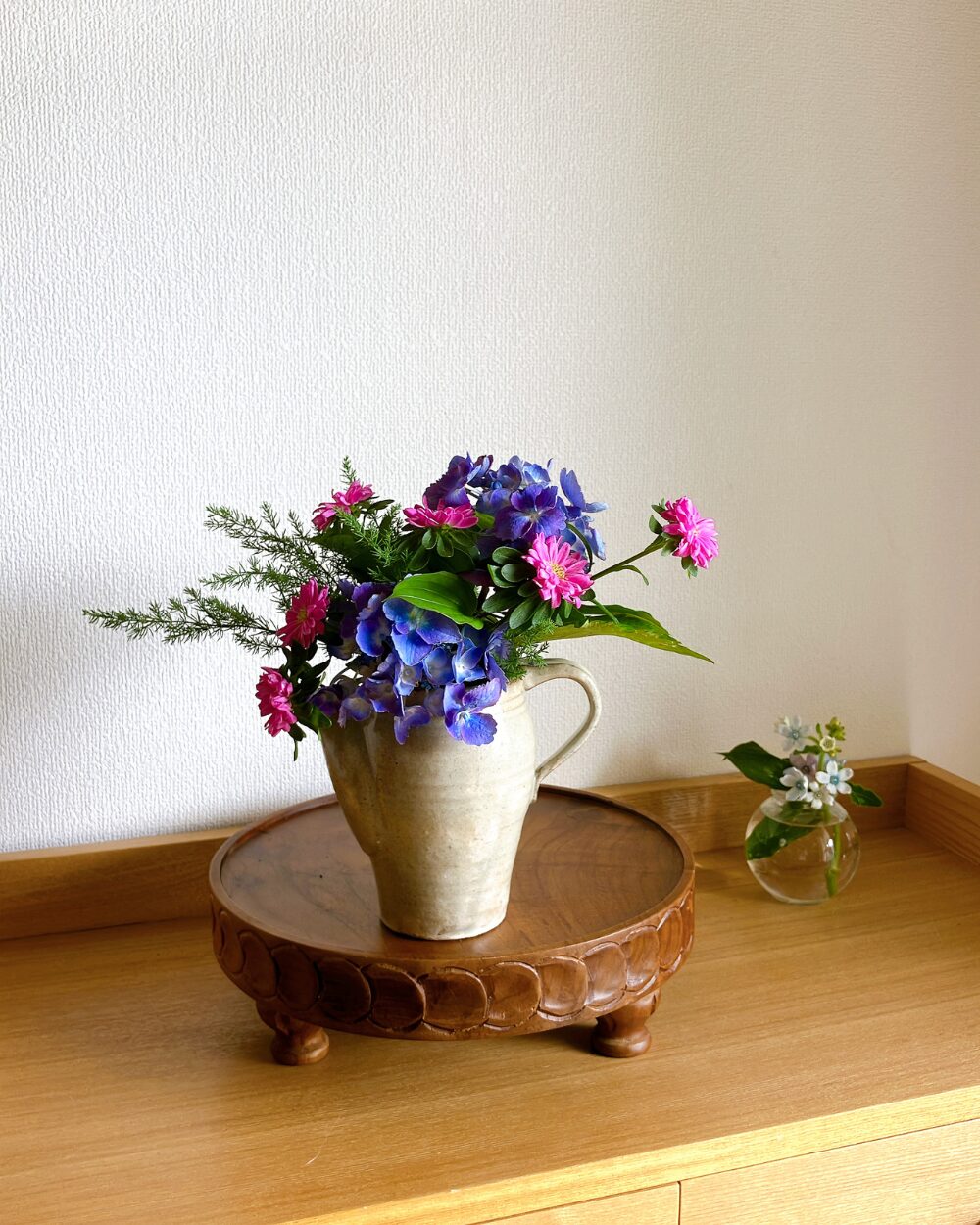 Hydrangea, aster, and greenery arranged inside a Japanese ceramic pitcher.