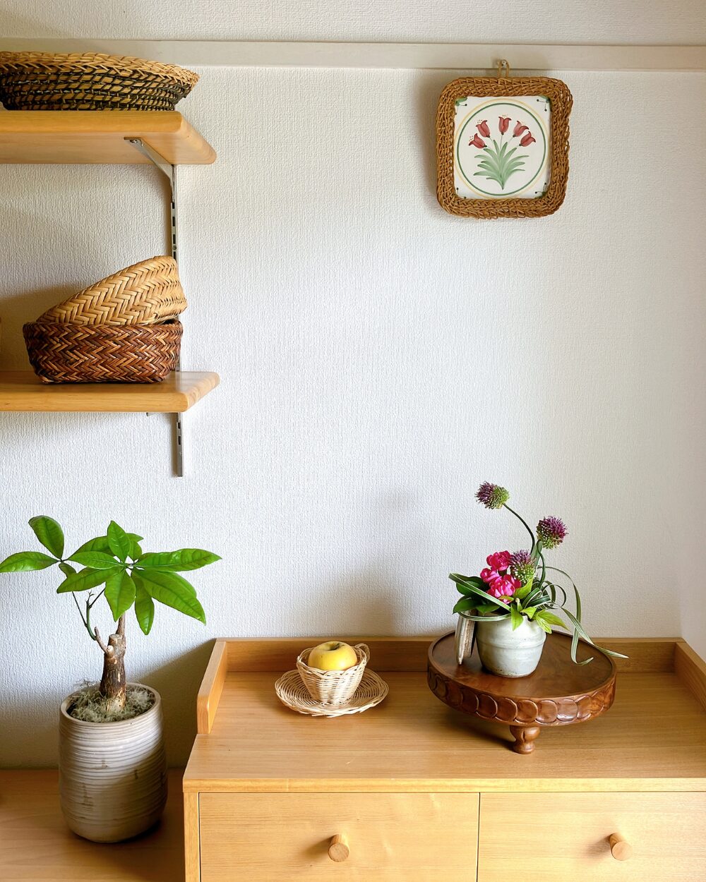 A wide view of the small Japanese ceramic jar with pink flowers and a yellow apple in the space.