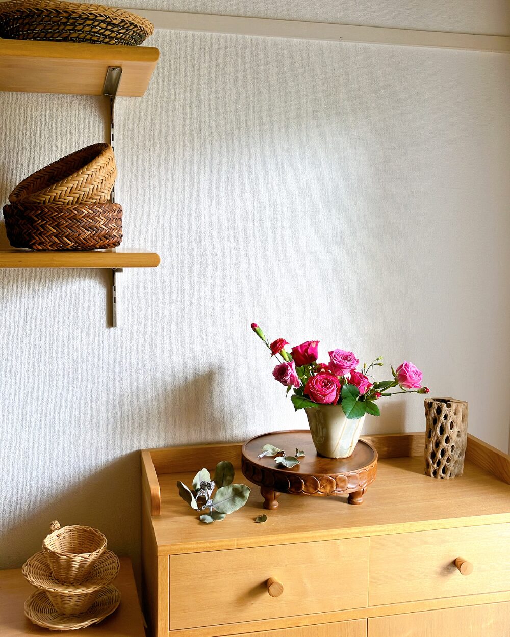 A wide shot of a minimal pink rose arrangement sitting quietly on a wooden living room shelf, styling the daily living space.
