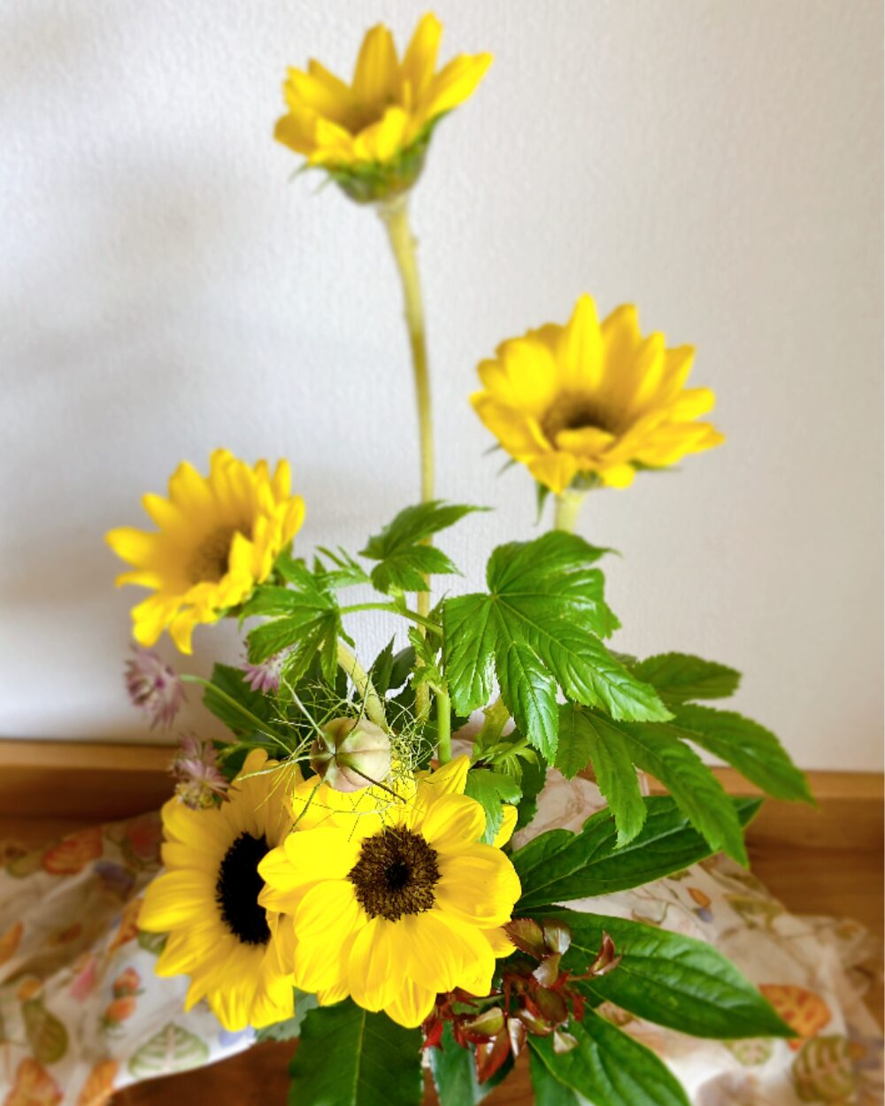 Overhead view of the five sunflower arrangement on a colorful scarf