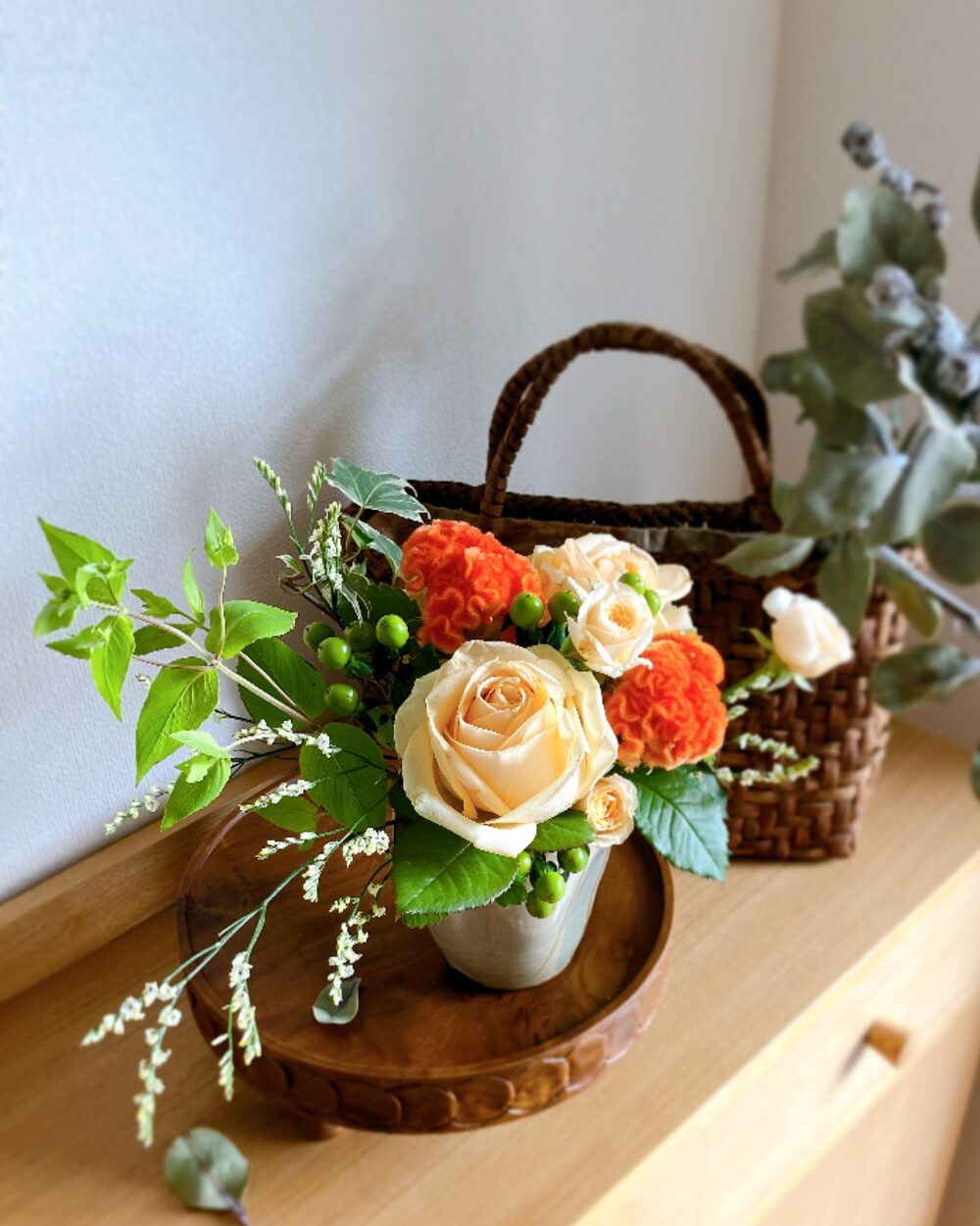 Looking directly down at a mounded orange rose arrangement, resembling a lush pile of fresh fruit overflowing from a Japanese plate.