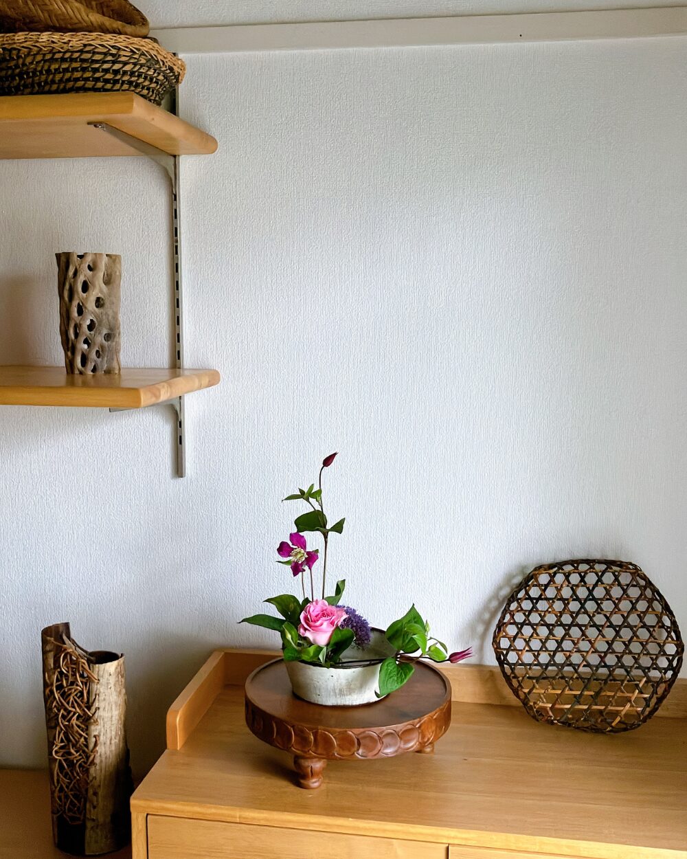 A wide interior shot showing a calm and settled single rose arrangement on a shelf, bringing a sense of stillness to the home environment.
