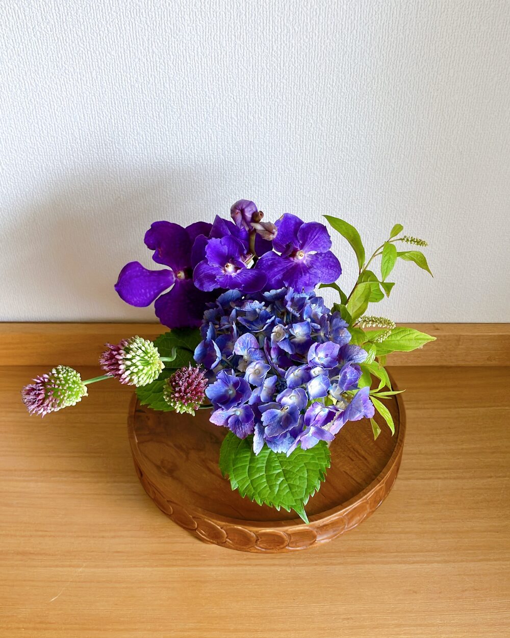 A top view of the hydrangea, vanda orchid, and allium in the ceramic vessel.