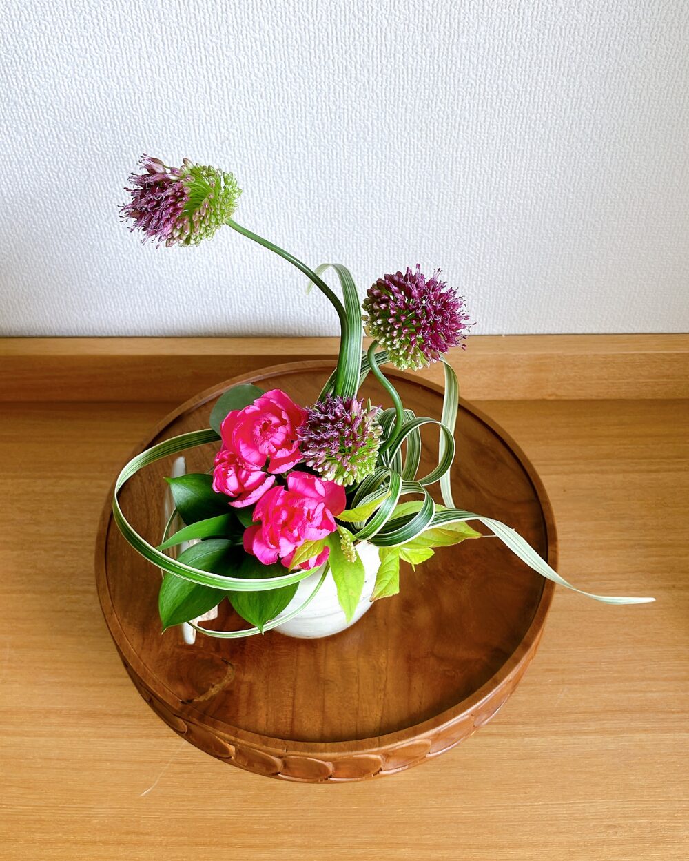 A top view of the flowers in the ceramic jar with a small yellow apple placed on the surface right beside it.